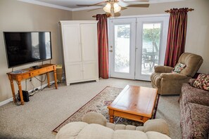 Un salon comprenant un téléviseur, un meuble, un canapé, une table basse et un tapis à motifs.