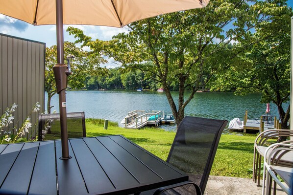 A patio with a table and chairs, overlooking a lake with boats.