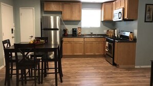 Una cocina moderna con armarios de madera, un refrigerador de acero inoxidable, una estufa a gas y un comedor con mesa y sillas.