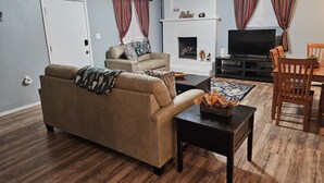Una sala de estar con sofá, mesa de centro, televisión, chimenea y comedor.