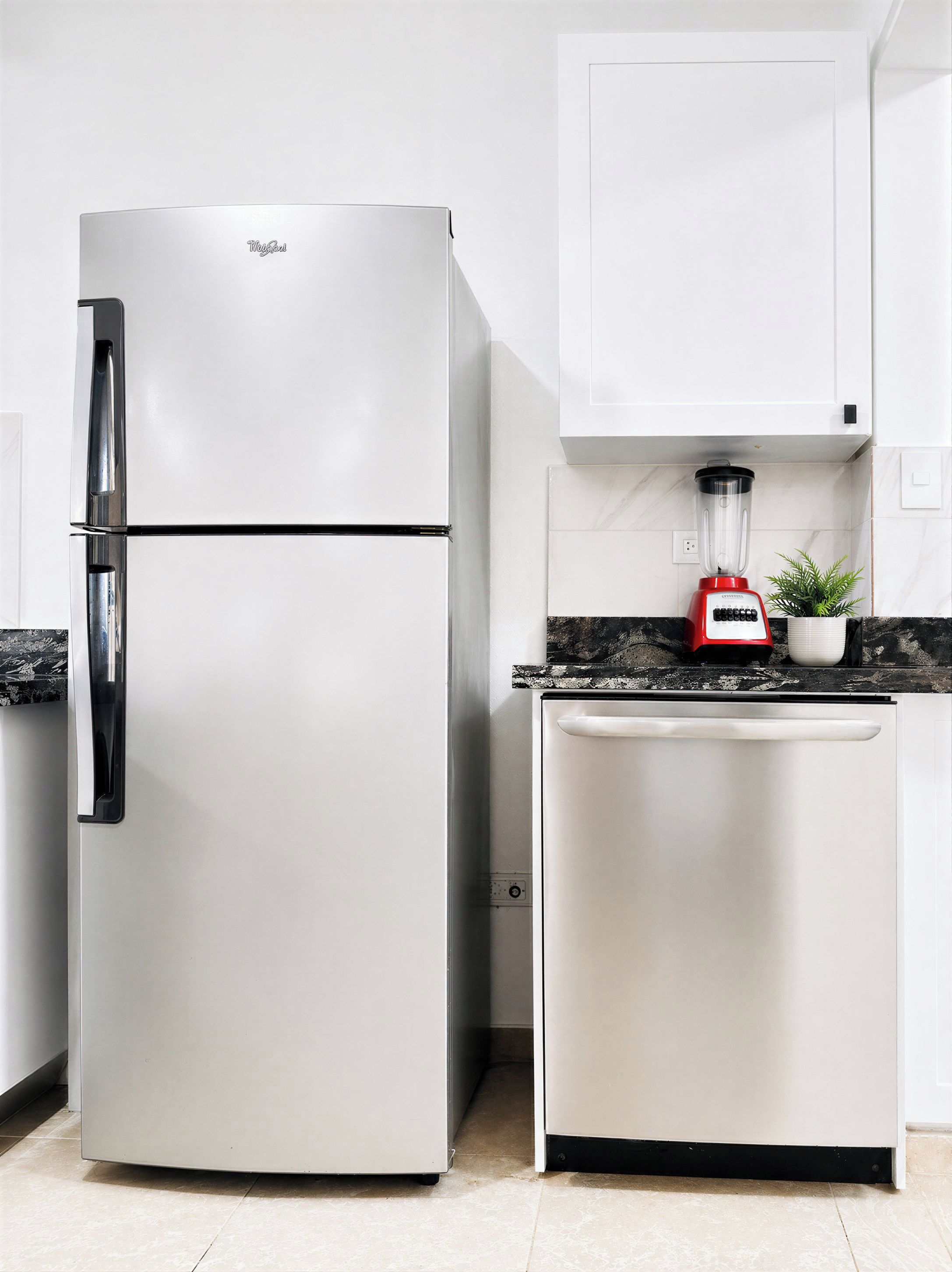A kitchen with a white refrigerator, a white dishwasher, and a red blender on the counter.
