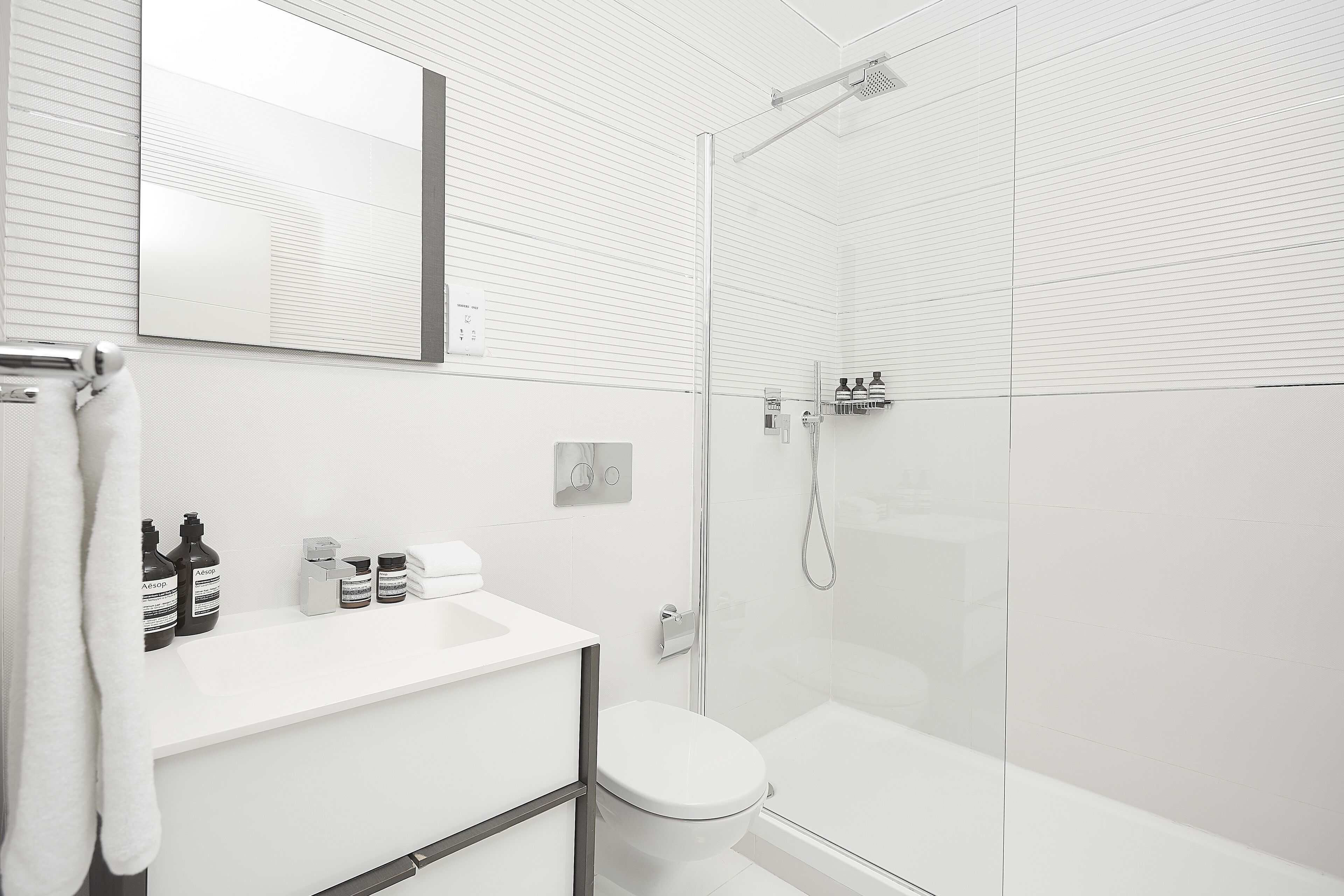 A modern bathroom with a white sink, toilet, and shower area.