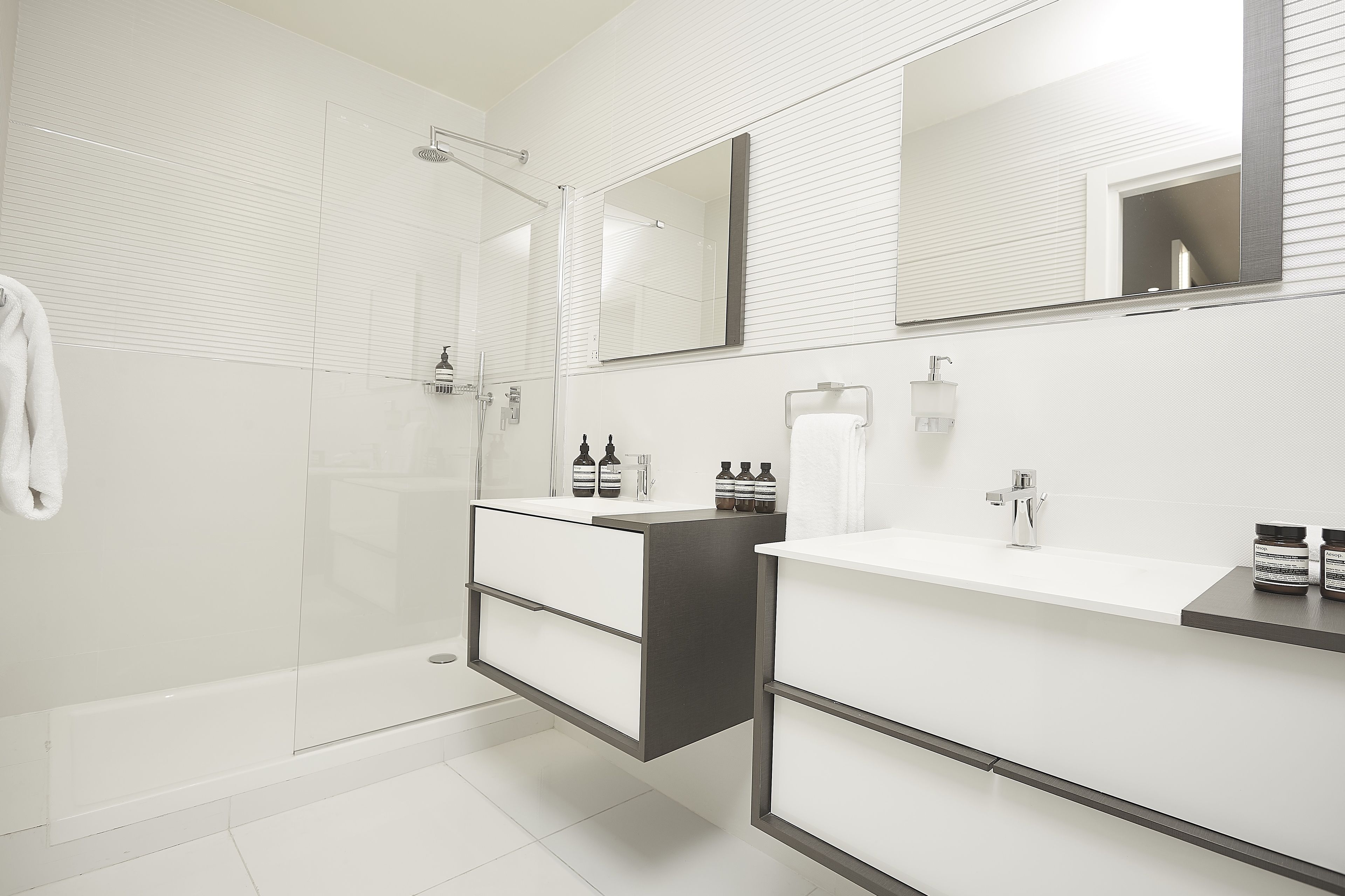 A modern bathroom with a glass shower enclosure, a vanity with a mirror, and a towel rack.