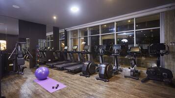 A gym with exercise equipment, a large window, and a purple mat.