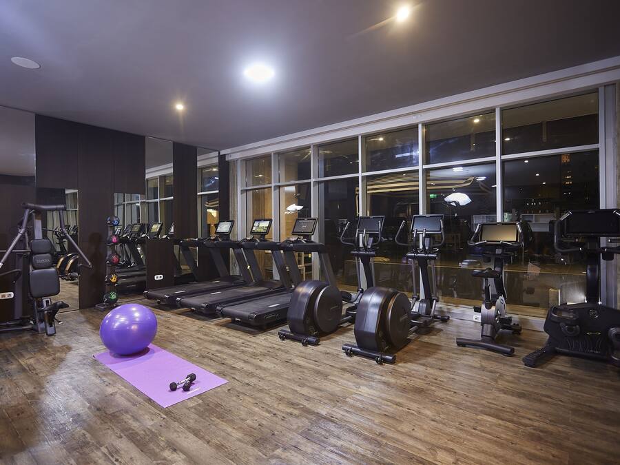 A gym with exercise equipment, a large window, and a purple mat.
