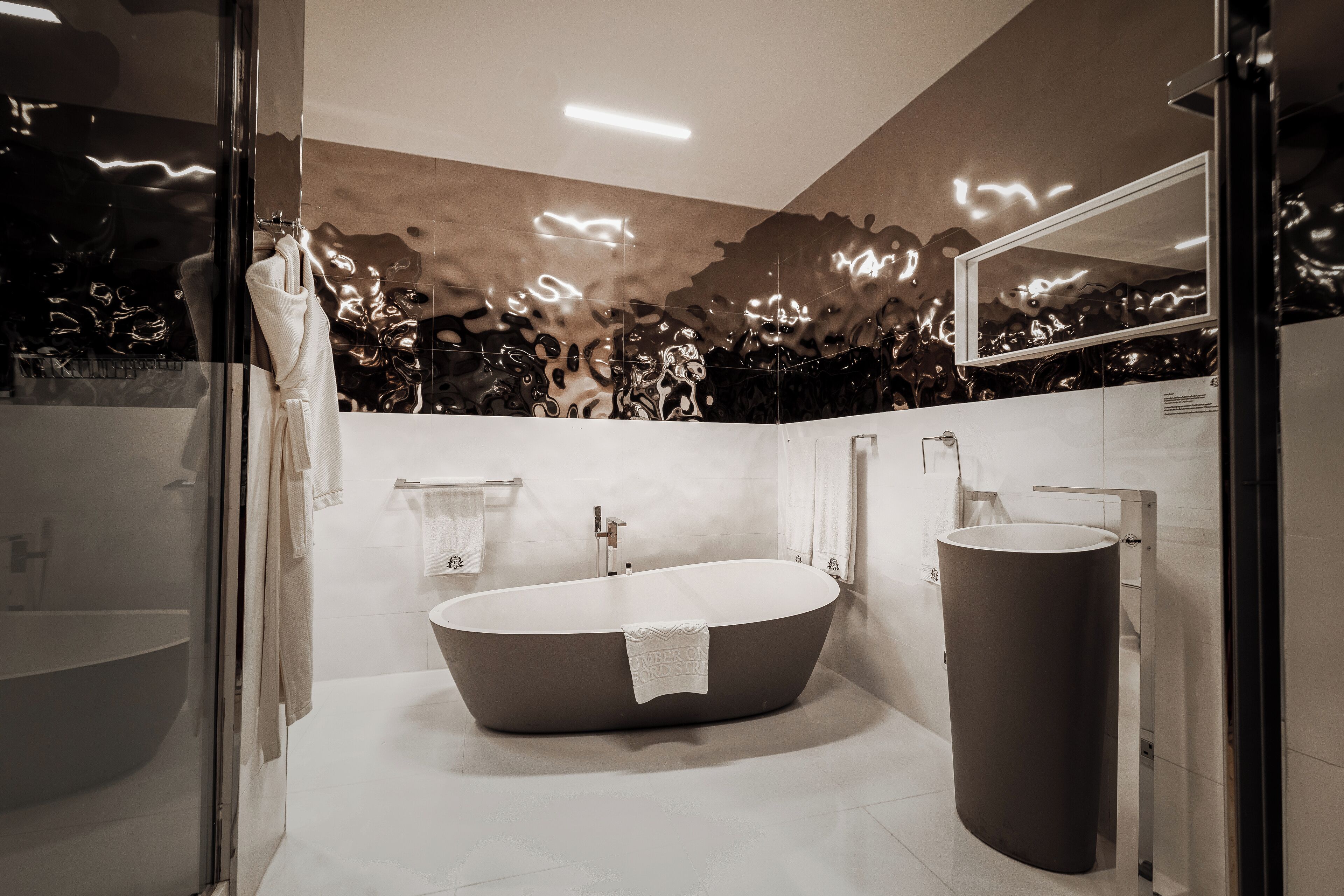 A modern bathroom with a freestanding bathtub, a round sink, and a large mirror.