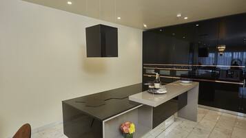 A modern kitchen with a sleek black countertop, a white island, and a vase of flowers.