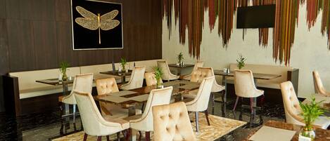 A modern dining area with a large butterfly artwork, a TV mounted on the wall, and a colorful vertical design.