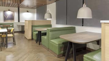 A restaurant interior with booths, tables, and hanging pendant lights.