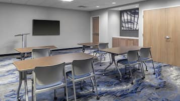 A conference room with a large table, chairs, a projector screen, and a carpeted floor.