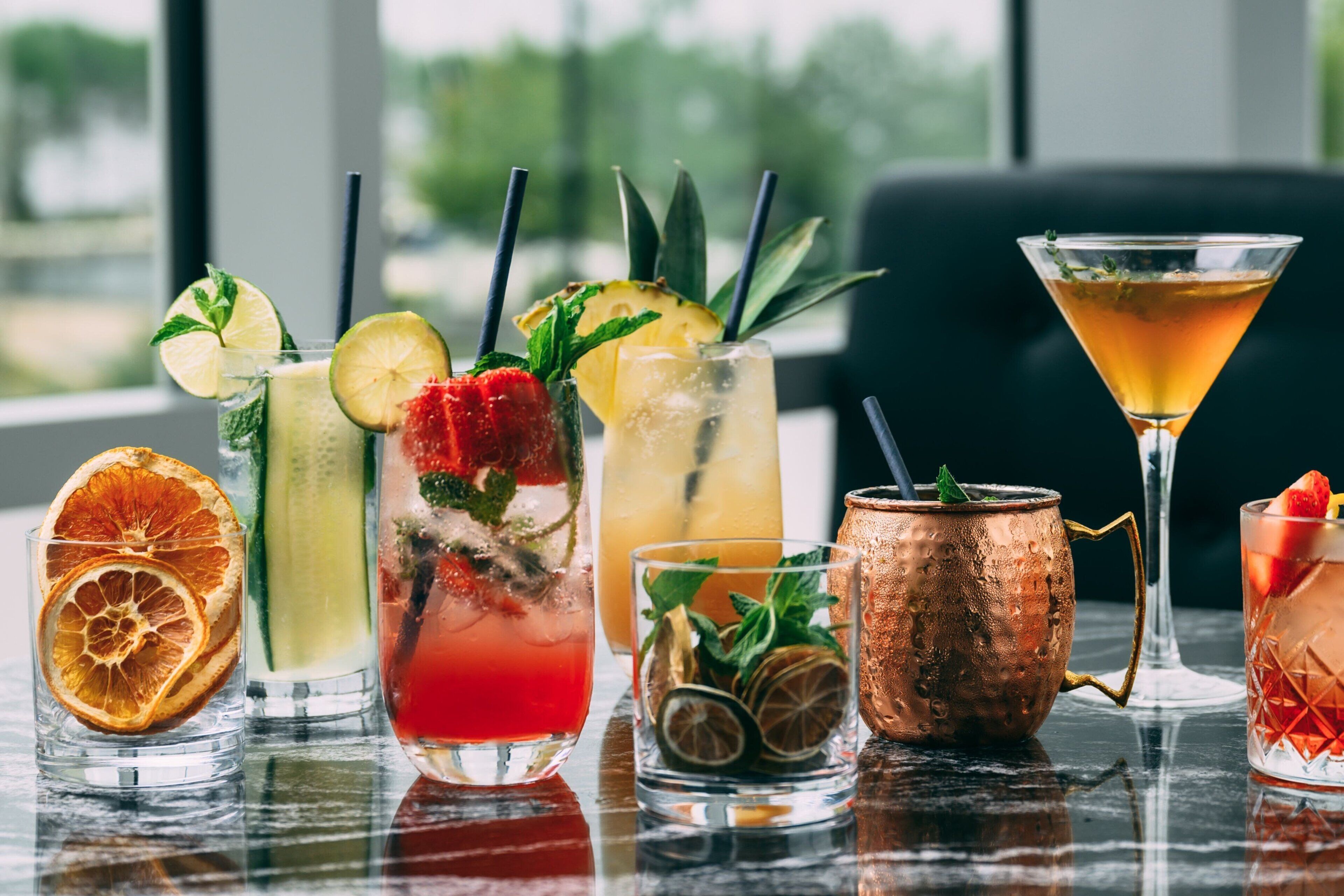 Variedad de bebidas sobre una mesa, con vista al exterior a través de una ventana.