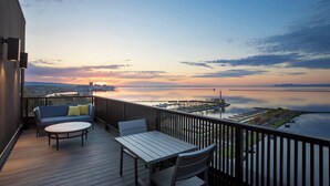 Ein Balkon mit Tisch und Stühlen, der auf ein ruhiges Gewässer und einen Hafenblick bietet.