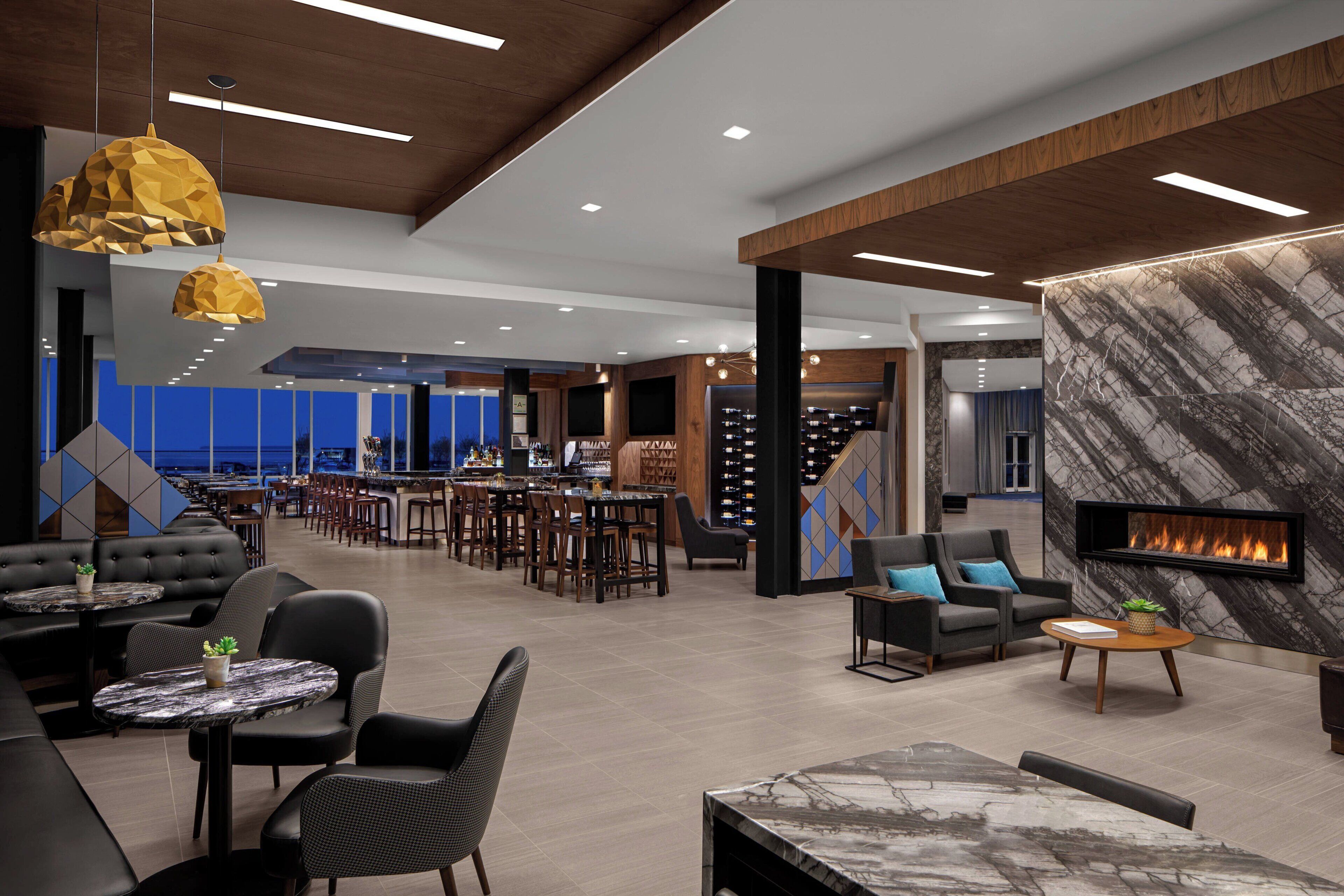 A modern lounge area with seating, a bar, and a fireplace.