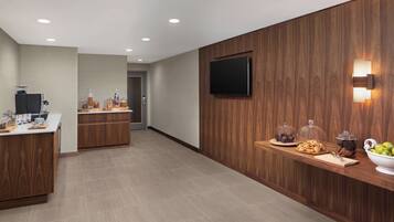 A modern kitchen with wooden cabinets, a central island, and a breakfast bar with snacks and a bowl of fruit.