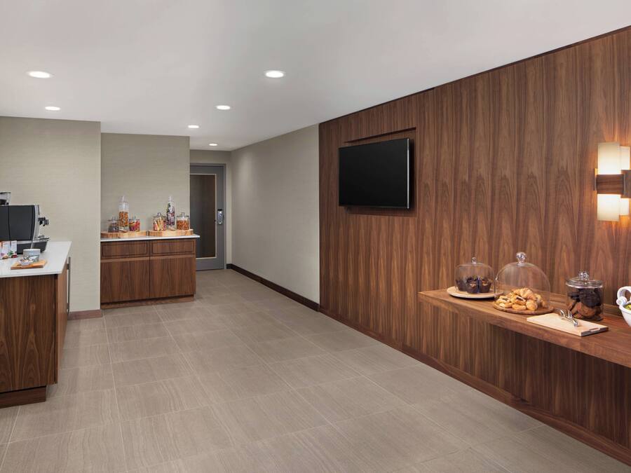 A modern kitchen with wooden cabinets, a central island, and a breakfast bar with snacks and a bowl of fruit.