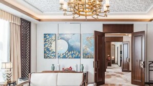 Un vestíbulo de hotel moderno con un sofá blanco, una araña y arte abstracto en las paredes.