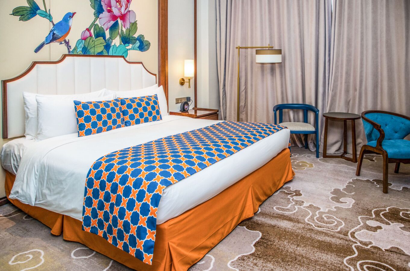 Ein Hotelzimmer mit einem großen Bett, einem Nachttisch, einem Sessel und einer Lampe.
