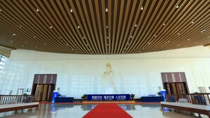 Un amplio salón con techo alto, un escenario central y una alfombra roja.