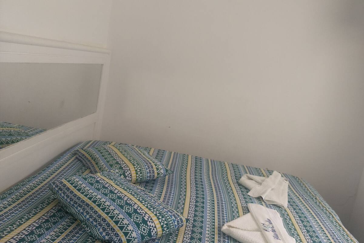 Een kleine eenpersoonskamer met een bedovertrek met dessin en een witte handdoek op het bed.