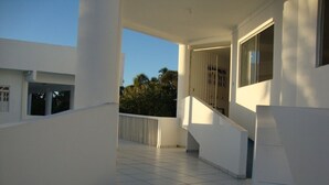 Un bâtiment moderne doté d’un balcon couvert, de murs blancs et d’un sol carrelé.