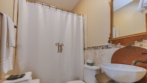 A bathroom with a white shower curtain, a white sink with a large bowl, a toilet, and a mirror with a wooden frame. - Weymouth Hall B&B (Natchez)