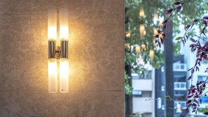 Eine Wandleuchte mit zwei vertikalen Lampen an einer strukturierten Wand.