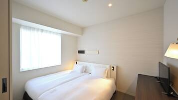Habitación de hotel con una cama grande, un escritorio, un televisor y un ventanal con cortinas.