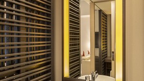 Ein modernes Badezimmer mit einem runden Waschbecken, einem großen Spiegel und einer Holztrennung.