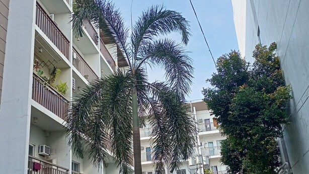 A multi-story residential building with balconies, air conditioning units, and a variety of potted plants. - Angel Travellers Transit House (Parañaque)