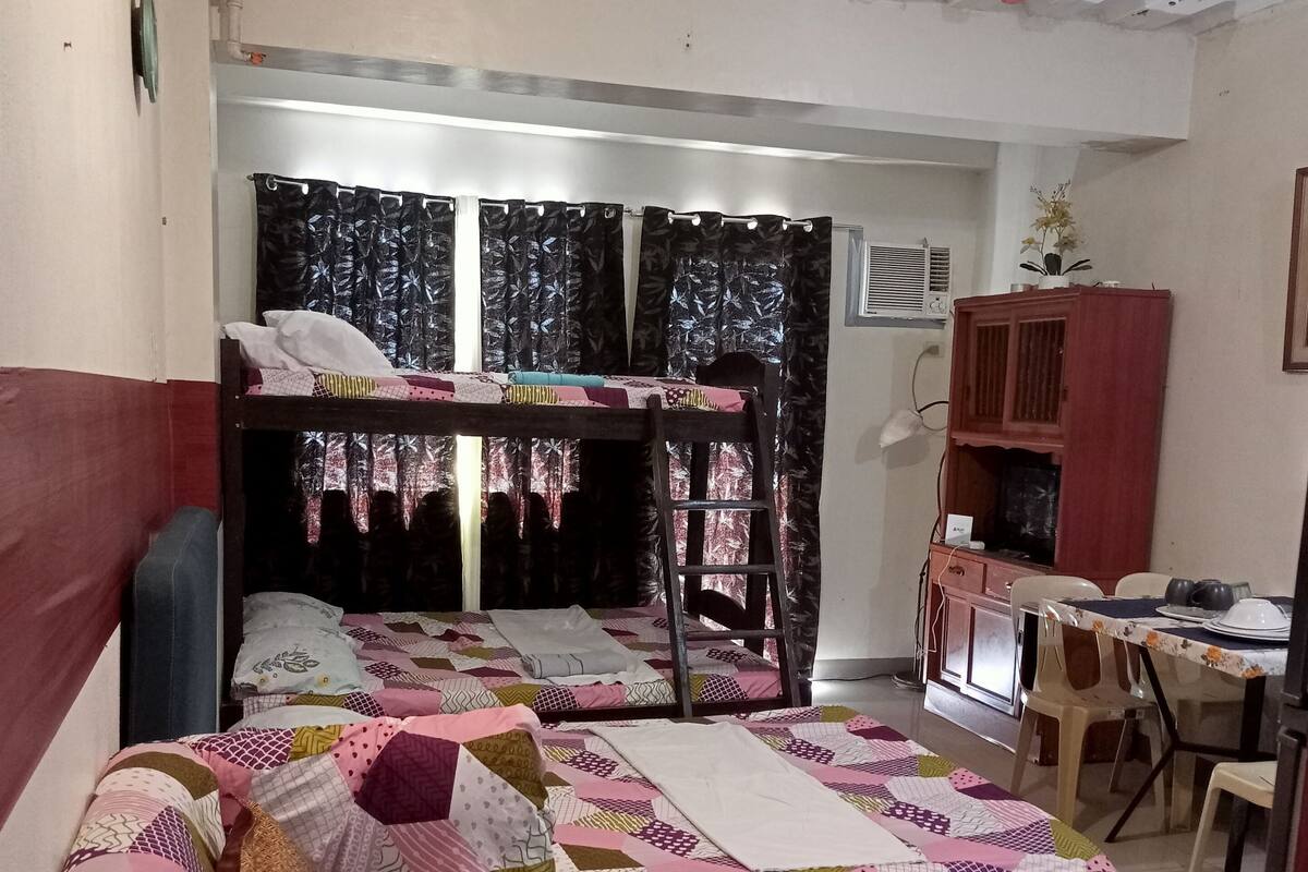 A dormitory room with bunk beds, a desk, and a chair.