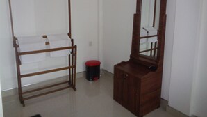 A room with a wooden bed frame, a small wooden cabinet, and a mirror. - Jungle View Guest (Polonnaruwa)