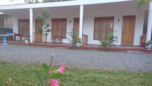 A building with a covered porch, wooden doors, and a gravel driveway. - Jungle View Guest (Polonnaruwa)