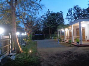A courtyard with a covered seating area, a fenced garden, and a building with large windows. - Jungle View Guest (Polonnaruwa)