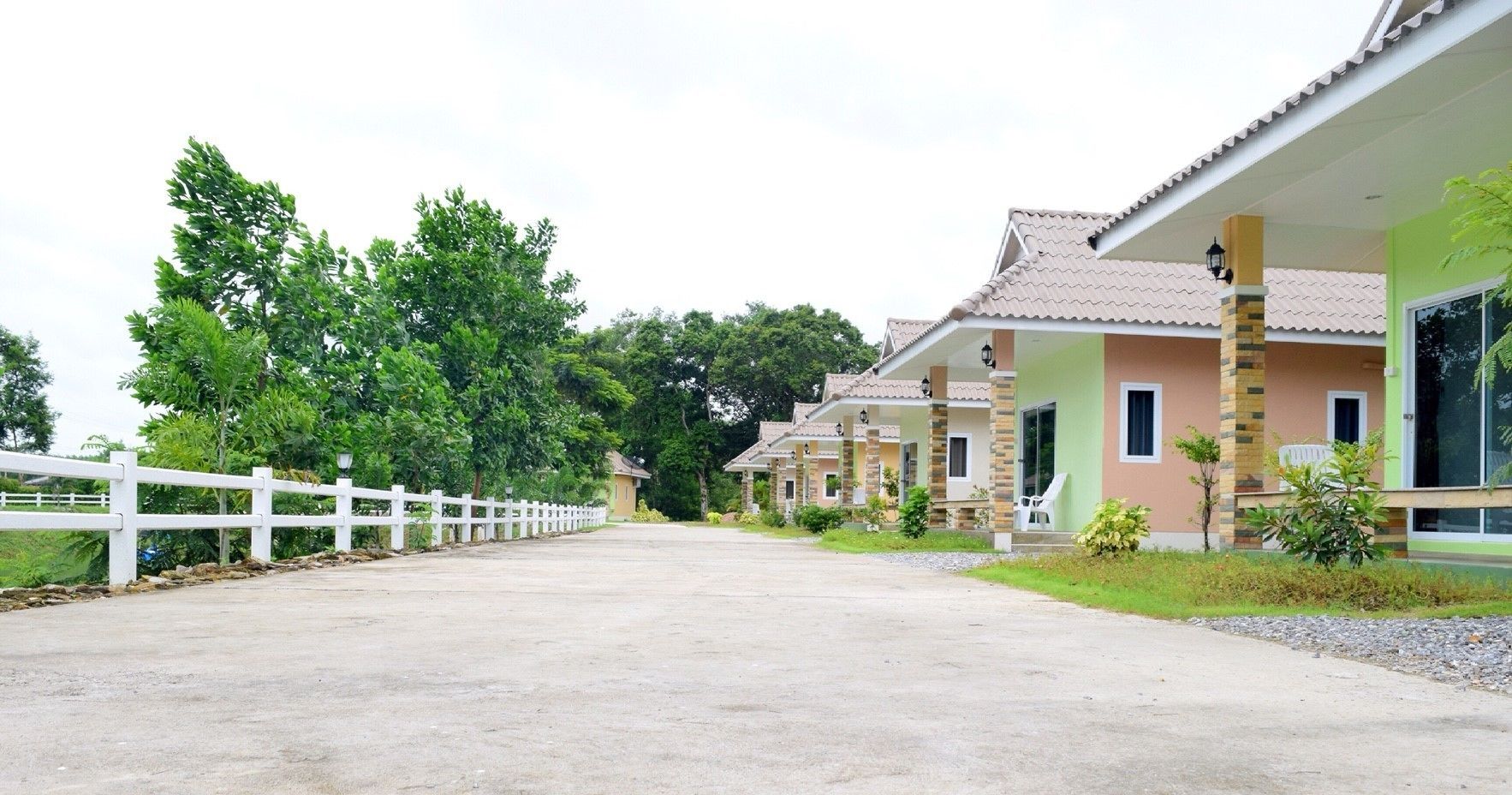 A row of single-story buildings with a white fence in the foreground, likely part of a resort or hotel complex.