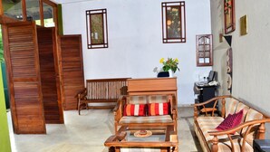 A cozy outdoor seating area with wooden furniture, including a sofa and a bench, and a small table. - Deer Point Hotel Kandy (Kandy)