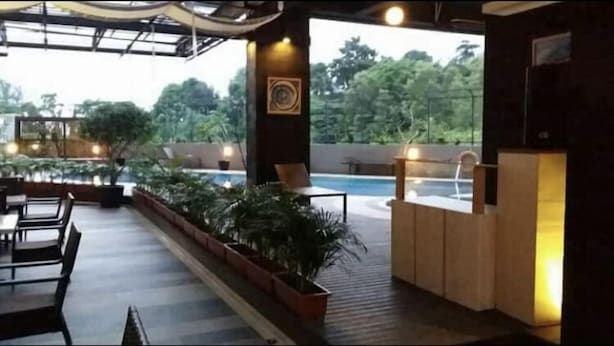 An outdoor seating area with tables and chairs, a pool, and potted plants. - Studio Apartment Nagoya Mansion Batam (Batam)