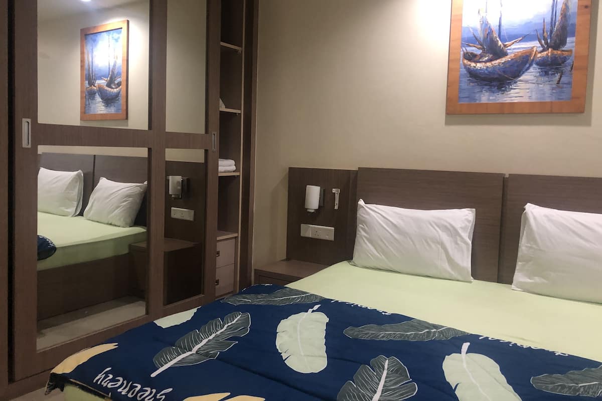 Ett hotellrum med en säng, en garderob och en tavla på väggen.