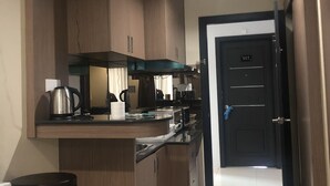 A compact kitchen with wooden cabinets, a countertop, and a door marked 'S17'. - Studio Apartment Nagoya Mansion Batam (Batam)