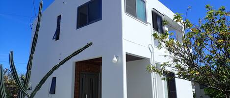 A modern two-story house with a flat roof, large windows, and a small porch area.