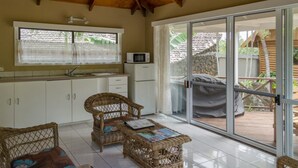 Une pièce comprenant une cuisine, un coin repas et une porte-fenêtre coulissante donnant sur une terrasse extérieure.