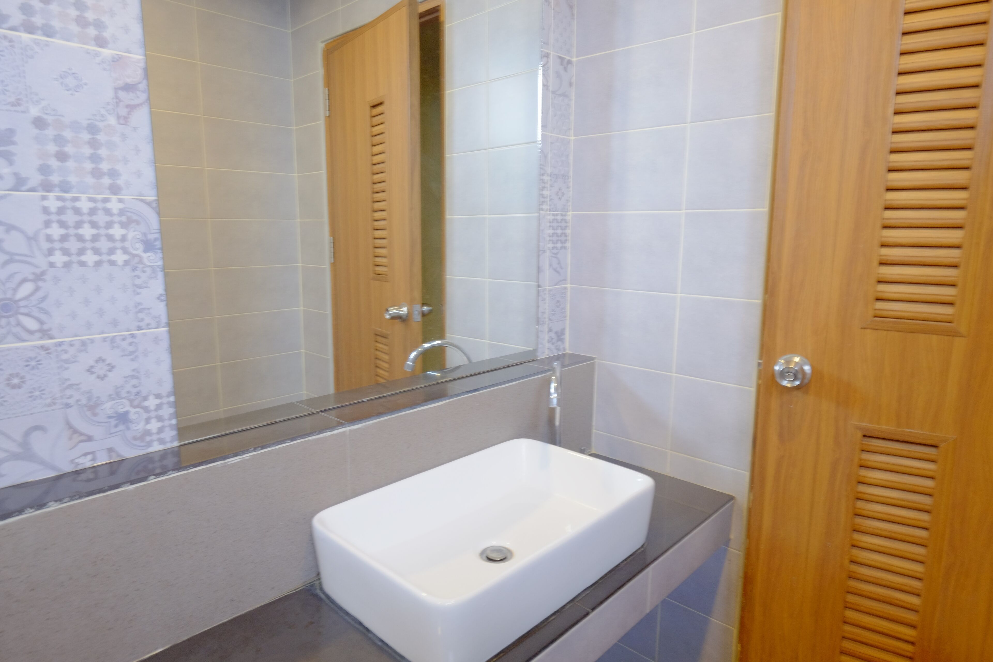 A bathroom with a white sink, a mirror, and wooden doors.