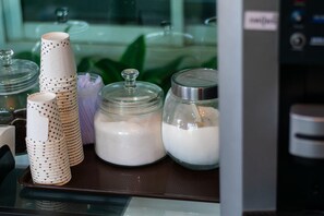 A kitchen counter with stacked paper cups, a glass jar with a lid, and a glass container with a lid.