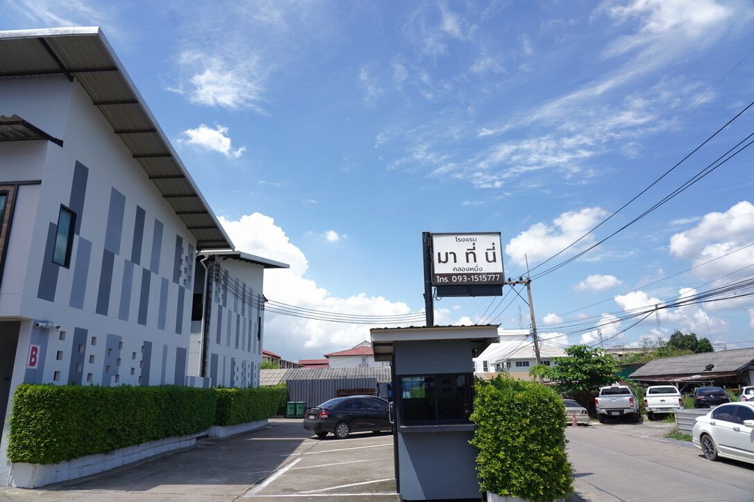 A building with a signboard, a parking lot, and a few parked cars.