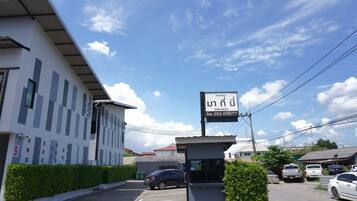 A building with a signboard, a parking lot, and a few parked cars.