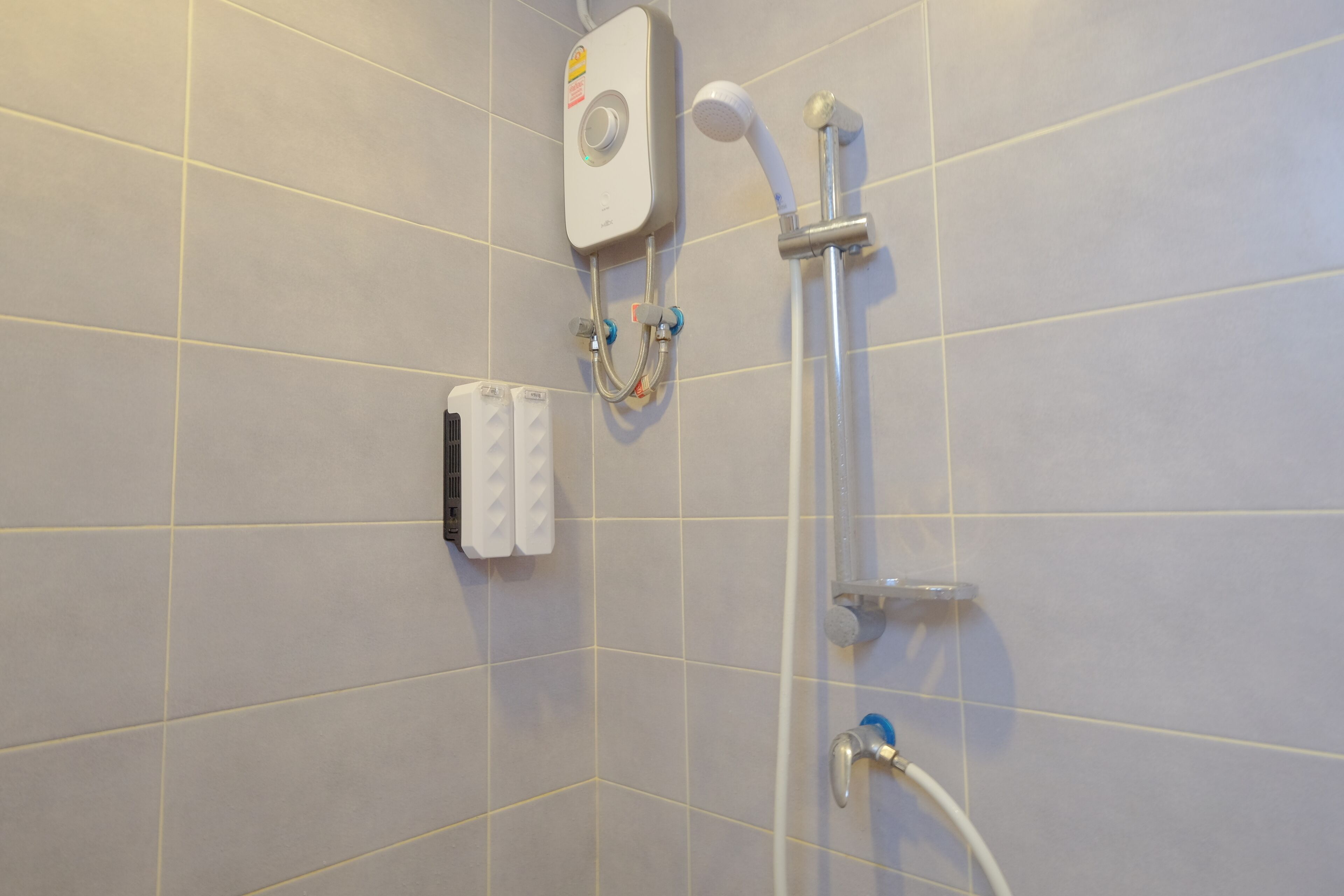 Une douche équipée d’un pommeau de douche à main et d’un panneau de commande fixé au mur.