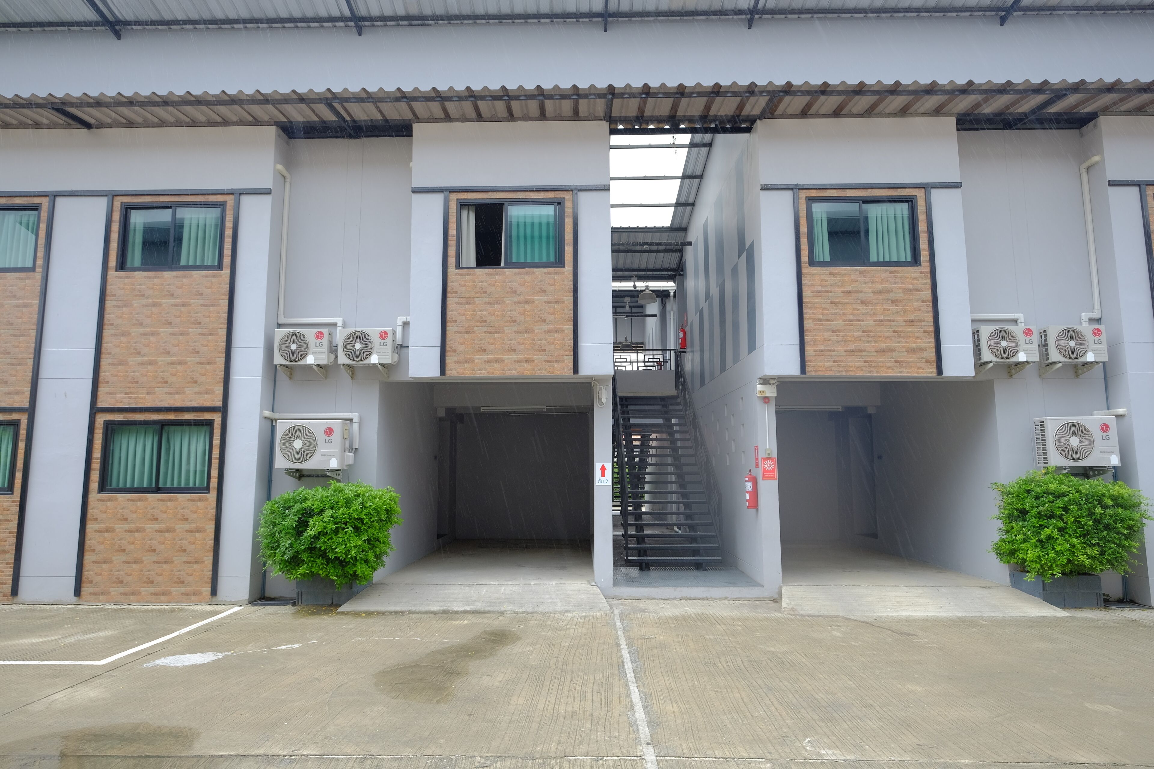 A building with two staircases, air conditioning units, and potted plants.