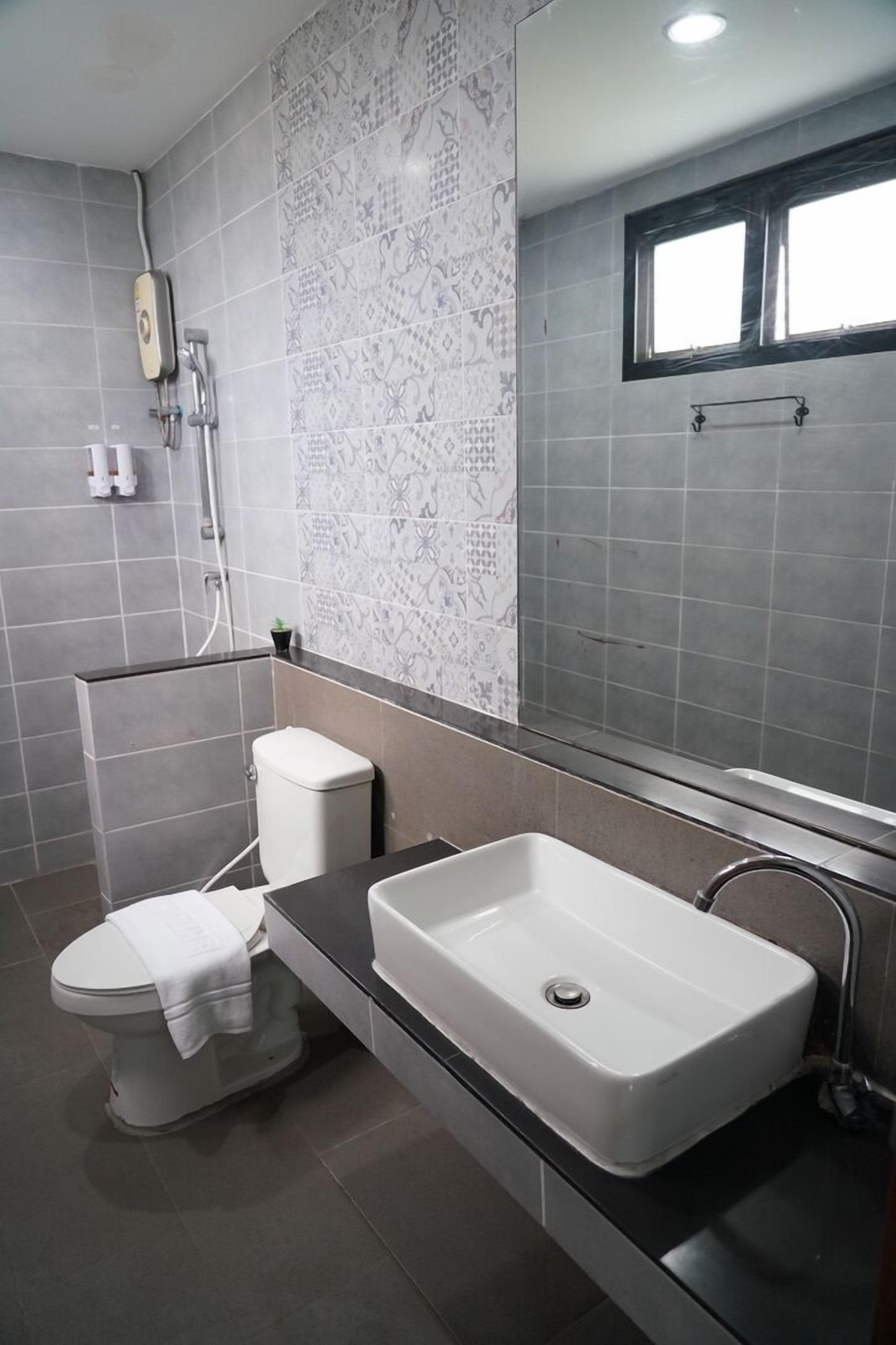 Un bagno moderno con il water bianco, un lavabo rettangolare capiente e uno specchio sopra al lavabo.