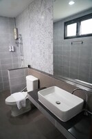 Un bagno moderno con il water bianco, un lavabo rettangolare capiente e uno specchio sopra al lavabo.