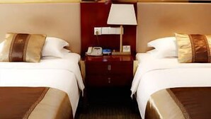 Ett hotellrum med två sängar, var och en med en brun sänggavel, ett nattduksbord med en lampa och en telefon.