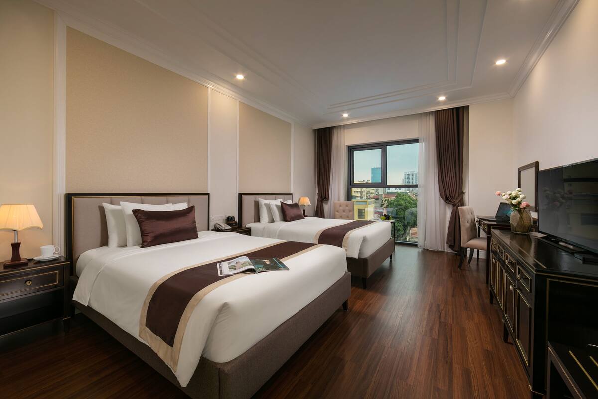 Une chambre d’hôtel avec deux lits, un bureau, une télévision et une vue sur la ville.